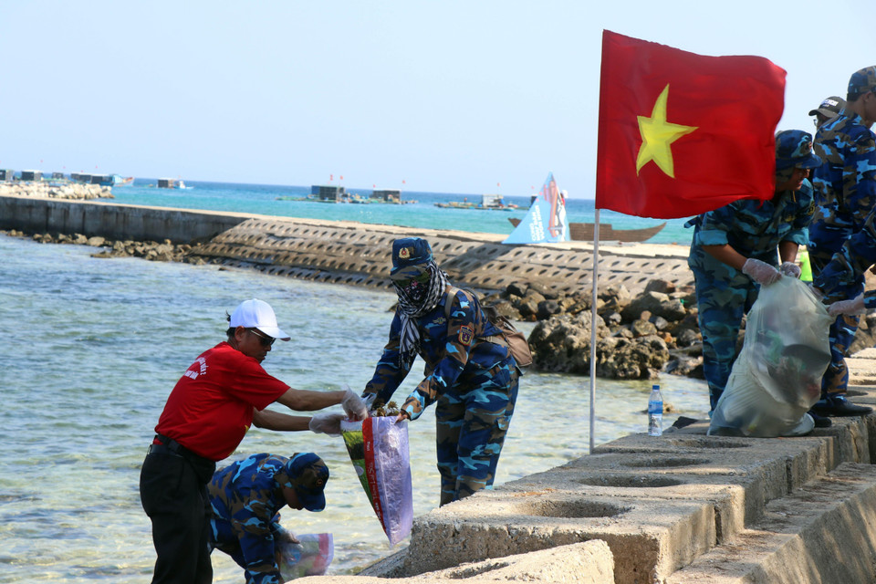 Chiến sỹ Vùng cảnh sát biển 2 phối hợp với thanh niên tình nguyện dọn vệ sinh môi trường biển tại huyện đảo Lý Sơn, Quảng Ngãi. (Ảnh: Trần Tĩnh/TTXVN)