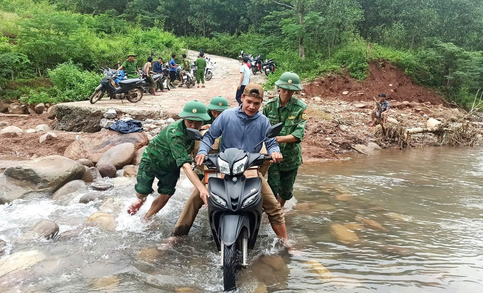 Cán bộ, chiến sỹ Đồn Biên phòng Ra Mai (Bộ đội Biên phòng Quảng Bình) hỗ trợ người dân, phương tiện đi qua các ngầm tràn, điểm giao thông đảm bảo an toàn. (Ảnh: TTXVN phát)