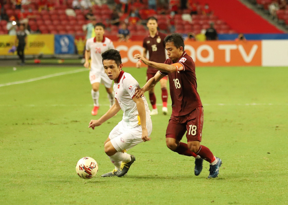 Nguyễn Phong Hồng Duy cố gắng triển khai bóng trước sự truy cản của Chanathip. (Ảnh: Thế Vũ/TTXVN)