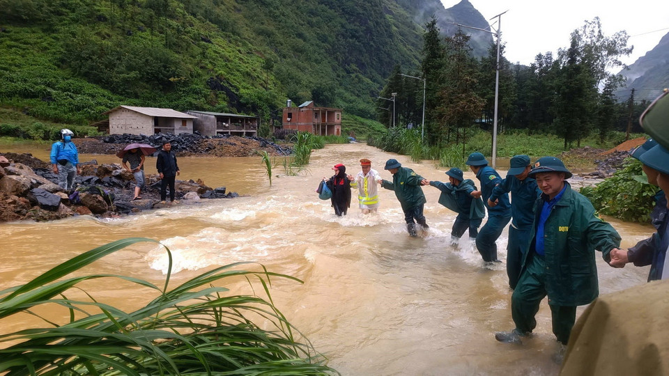 Lực lượng chức năng huyện Mèo Vạc (Hà Giang) hỗ trợ nhân dân xã Pả Vi đi qua khu vực nước lũ. (Ảnh: TTXVN )phát