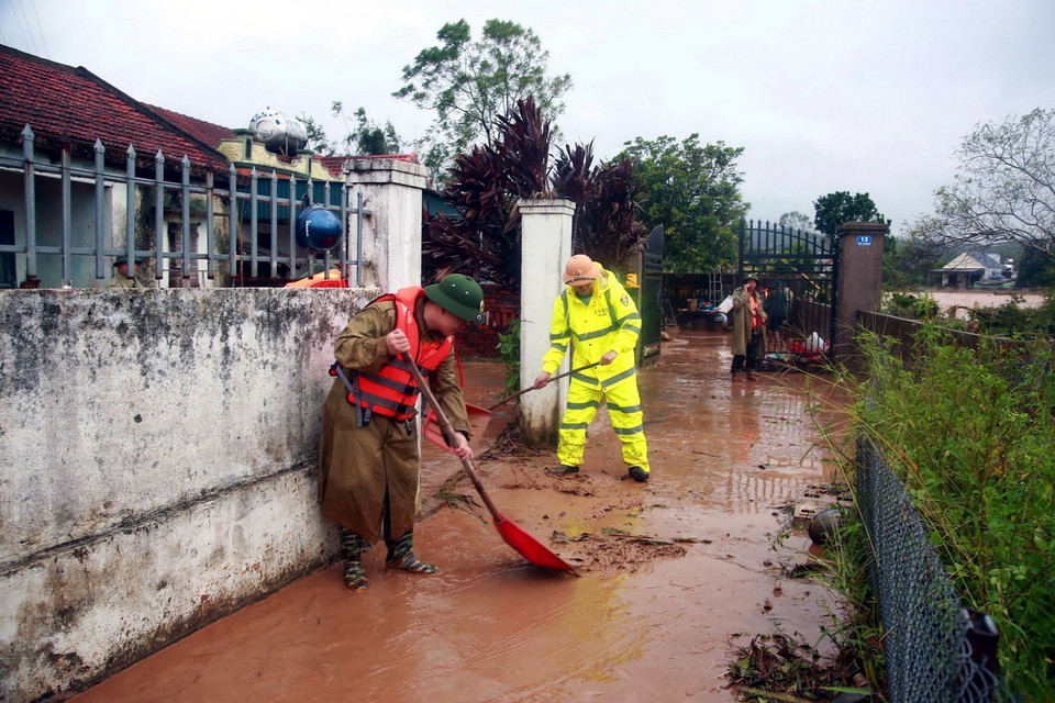 Lực lượng Công an và Cảnh sát hỗ trợ người dân thu dọn bùn đất. (Ảnh: TTXVN phát)