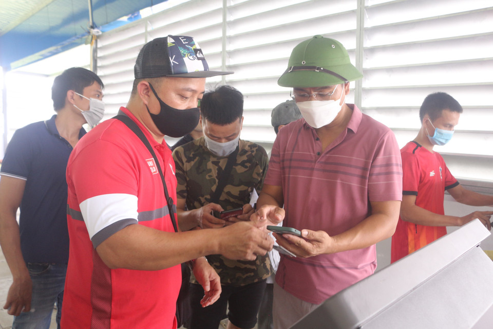 Đối với người chưa thành thạo sẽ được các lực lượng tại chốt hướng dẫn khai báo tự động. (Ảnh: Thanh Vân/TTXVN)