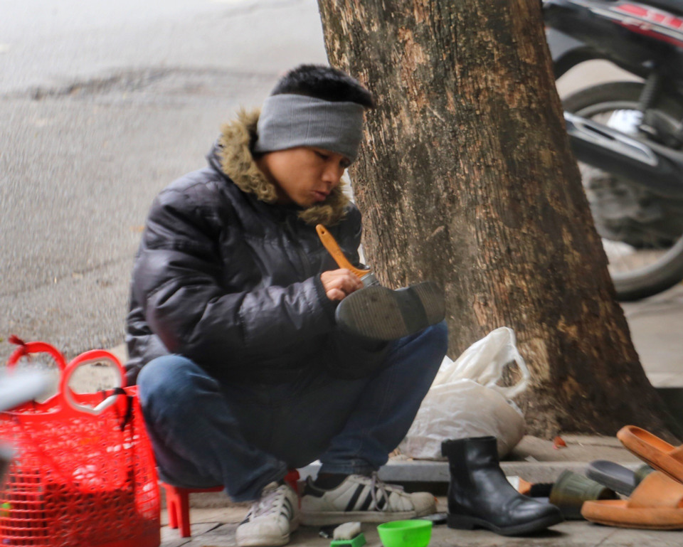Một người đánh giày trên phố khi nền nhiệt độ xuống đến 11 độ C. (Ảnh: Tuấn Đức/TTXVN)
