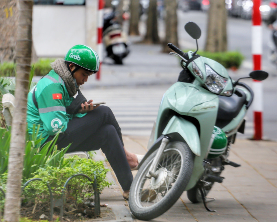 Một tài xế công nghệ ngồi nghỉ dưới cái lạnh "cắt da, cắt thịt". (Ảnh: Tuấn Đức/TTXVN)