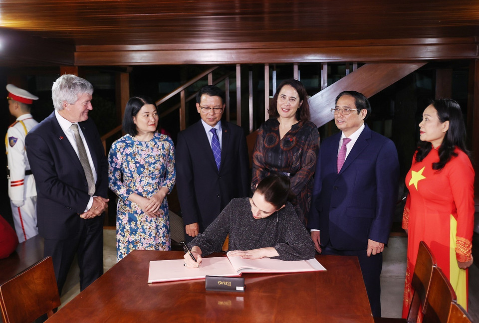 Thủ tướng Phạm Minh Chính chứng kiến Thủ tướng New Zealand Jacinda Ardern viết cảm tưởng sau khi thăm Nhà sàn Bác Hồ. (Ảnh: Dương Giang/TTXVN)