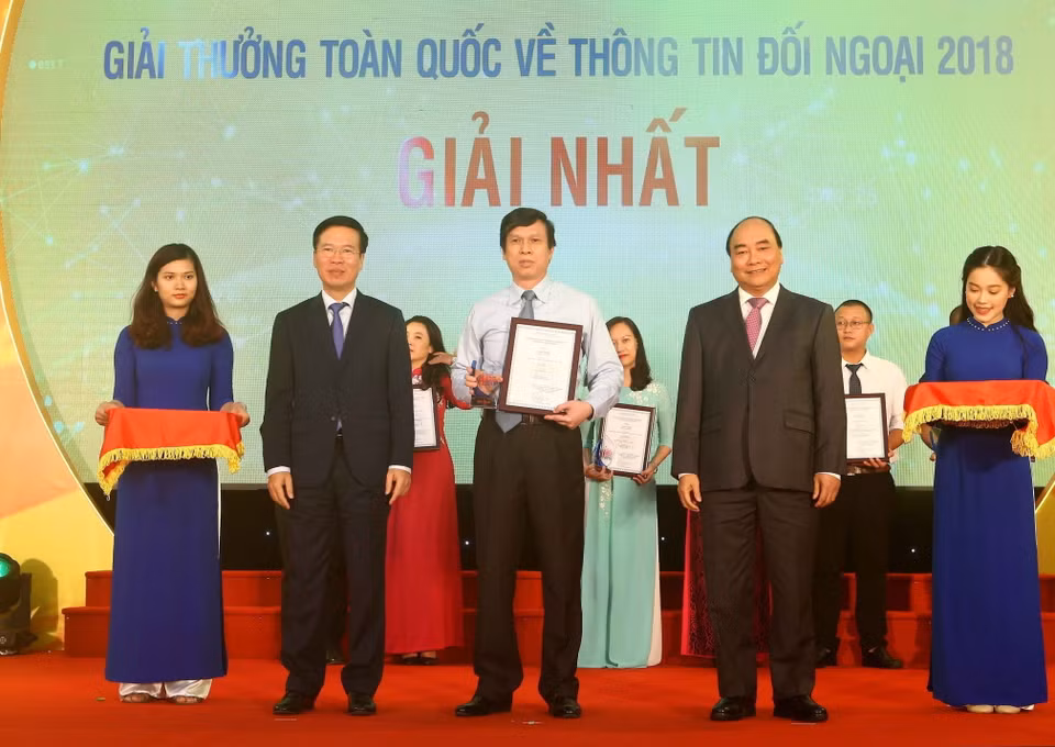 Thủ tướng Nguyễn Xuân Phúc và Trưởng ban Tuyên giáo Trung ương, Trưởng ban Chỉ đạo Công tác thông tin đối ngoại Trung ương Võ Văn Thưởng trao giải nhất Giải thưởng toàn quốc thông tin đối ngoại năm 2018 cho tác giả Lê Trí Dũng (TTXVN), ngày 7/6/2019, tại Trung tâm Thông tấn quốc gia Hà Nội. (Ảnh: Doãn Tấn/TTXVN)