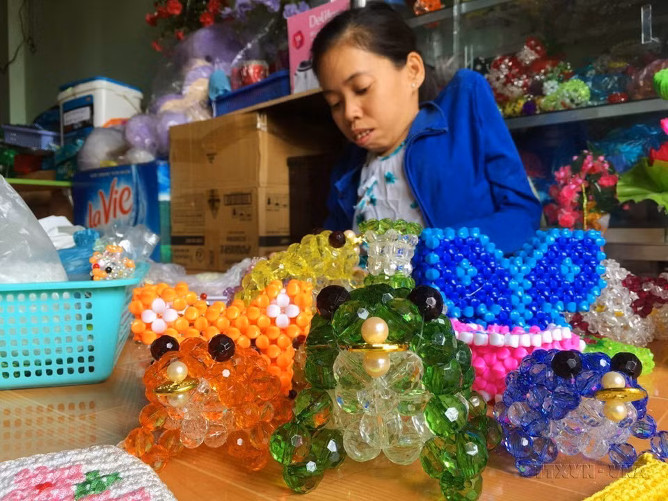 Chị Trần Kim Phượng (40 tuổi) ở phường Lê Bình, quận Cái Răng, thành phố Cần Thơ, nạn nhân chất độc da cam. Dù cơ thể tàn tật do nhiễm độc, sức khỏe yếu nhưng chị đã vượt lên hoàn cảnh, quyết vươn lên theo học nghề kết cườm, tạo việc làm có thu nhập cho bản thân. (Ảnh: Thanh Liêm/TTXVN)