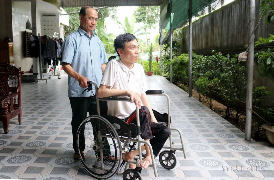 Thương binh Nguyễn Đình Duyên (bản Hốc, xã Châu Đình, huyện Quỳ Hợp, tỉnh Nghệ An) - Dũng sỹ diệt Mỹ, cùng đồng đội bắn rơi 6 máy bay địch trong một trận đấu, bên người con trai bị nhiễm chất độc da cam. (Ảnh: Văn Tý/TTXVN)