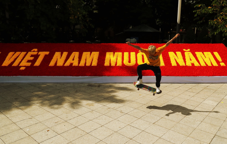 Một thanh niên chơi patin bên cạnh bảng hoa chào mừng Quốc khánh 2/9 tại Công viên Lê Nin. (Ảnh: Lâm Khánh/TTXVN)