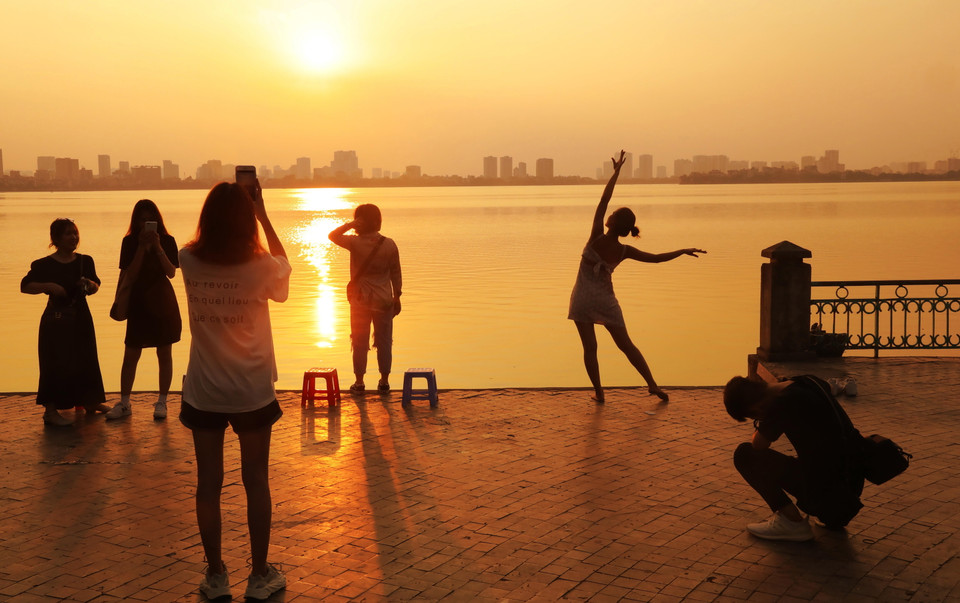 Những bạn trẻ đến thư giãn, chụp ảnh với hoàng hôn bên Hồ Tây. (Ảnh: Lâm Khánh/TTXVN)