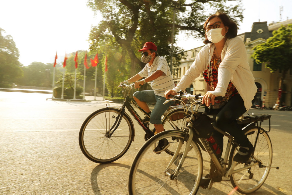 Người dân đạp xe buổi sáng bên tượng đài Lý Thái Tổ, Hoàn Kiếm. (Ảnh: Lâm Khánh/TTXVN)