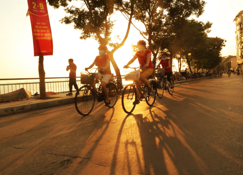 Người dân đạp xe trong nắng sớm bên Hồ Tây. (Ảnh: Lâm Khánh/TTXVN)