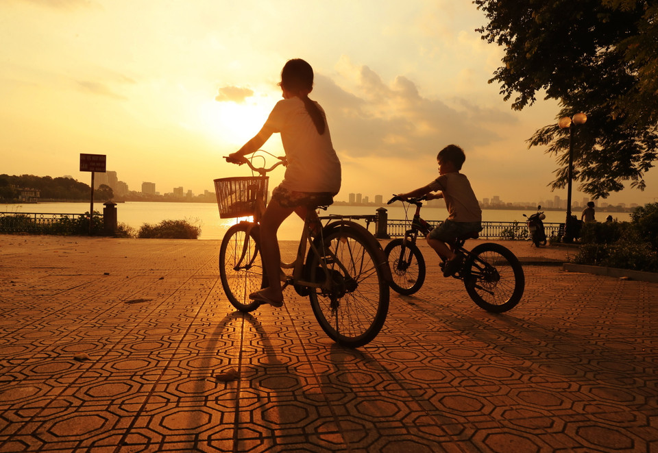 Trẻ em đạp xe, vui chơi bên Hồ Tây. (Ảnh: Lâm Khánh/TTXVN)