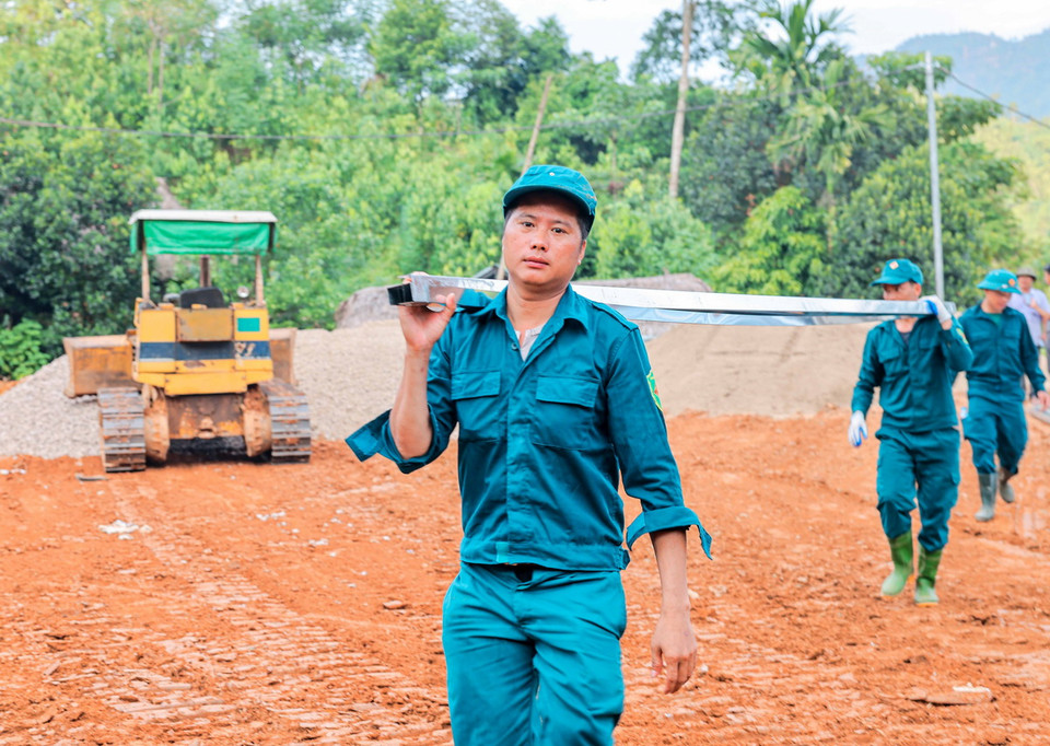 Lực lượng dân quân hỗ trợ chuyển vật liệu xây dựng vào khu vực thi công xây lắp nhà tạm. (Ảnh: Hoàng Hiếu/TTXVN)