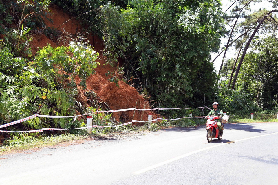 Nhiều khối đất và cây rừng đã bị trượt xuống mương thoát nước và một phần mặt đường Quốc lộ 28. (Ảnh: Ngọc Minh/TTXVN)