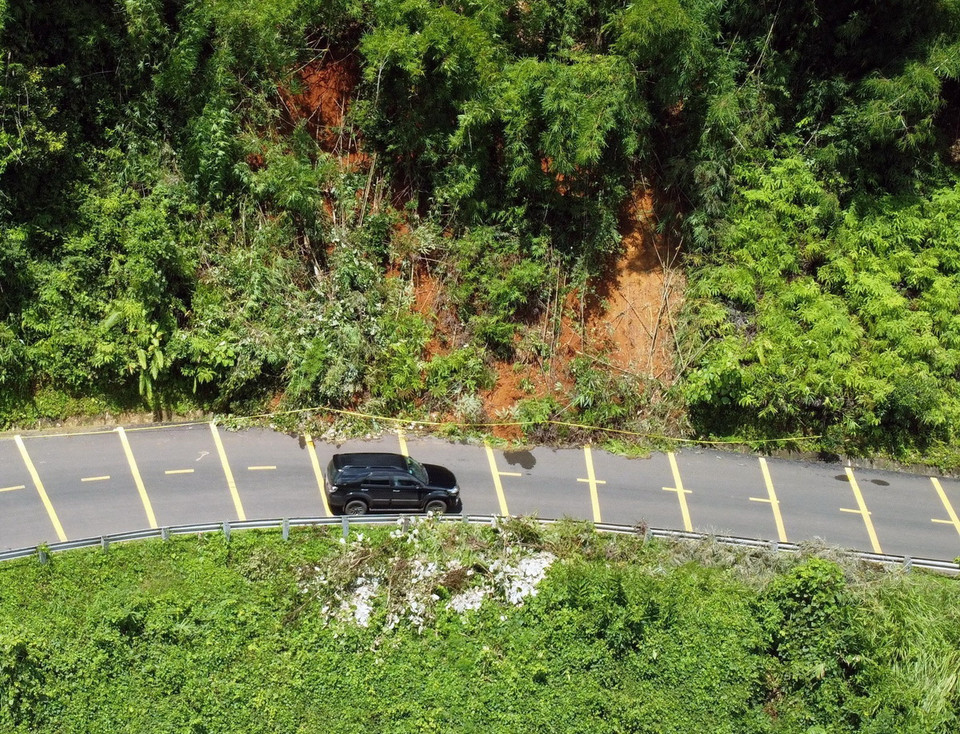 Nhiều khối đất và cây rừng đã bị trượt xuống mương thoát nước và một phần mặt đường Quốc lộ 28. (Ảnh: Ngọc Minh/TTXVN)