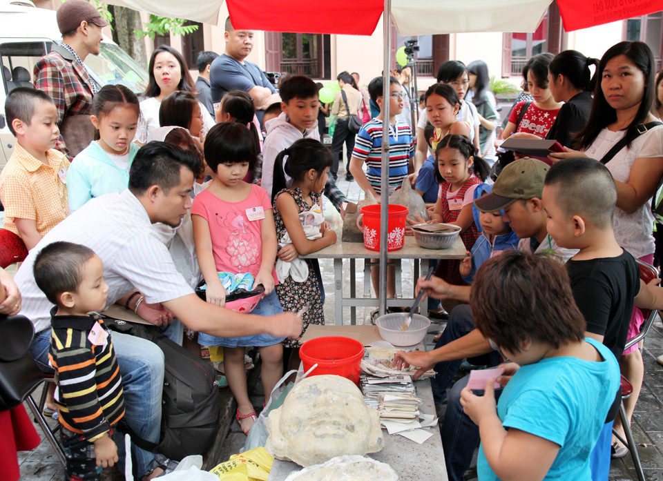 Các nghệ nhân bồi những lớp giấy bản chồng lên nhau bằng hồ nếp để tạo ra một chiếc mặt nạ vừa nhẹ, vừa cứng.(Ảnh: Doãn Đức/Vietnam+)