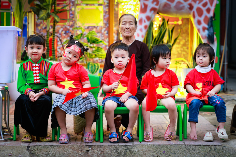 Những em nhỏ với trang phục rực rỡ cờ hoa theo người lớn đi xem diễu binh, diễu hành. (Ảnh: Hải An/Vietnam+)