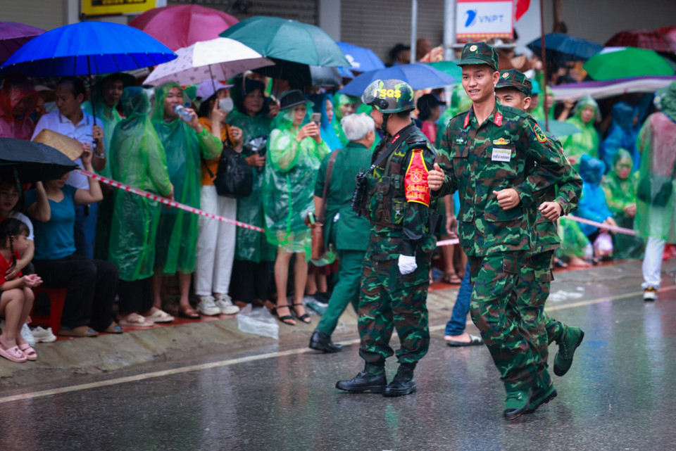 Dù trời mưa, nhiều người dân, du khách không muốn bỏ lỡ cơ hội được sống cùng không khí hào hùng với người dân Điện Biên để đi xem, cổ vũ diễu binh, diễu hành. (Ảnh: Hải An/Vietnam+)