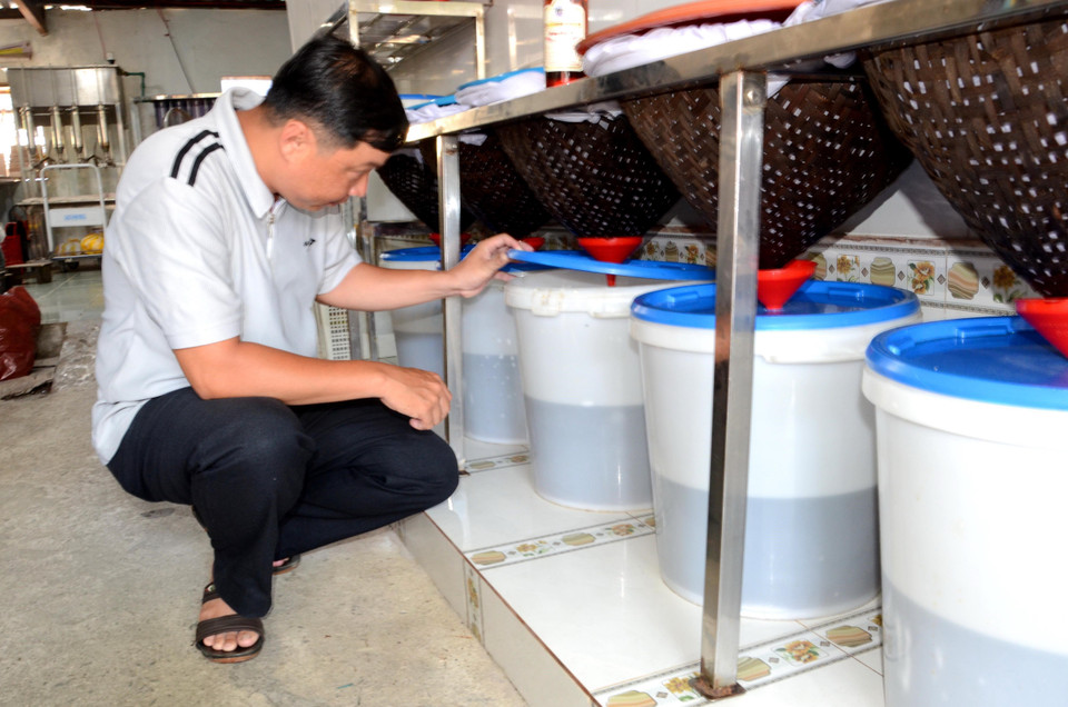 Sau khi ủ 12 tháng, mắm đã chín ngấu được lọc qua một phễu tre lót 2 lớp vải, quá trình này giúp nước mắm có màu trong và đẹp. (Ảnh: Quốc Dũng/TTXVN)