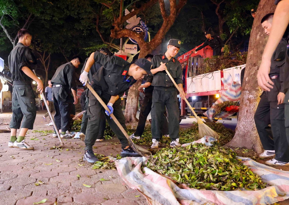 Cán bộ, chiến sỹ Cảnh sát cơ động dọn dẹp vệ sinh trên phố Phan Đình Phùng, quận Ba Đình trong đêm 14 rạng sáng 15/9. (Ảnh: Phạm Kiên/TTXVN)