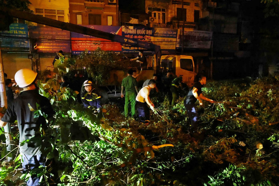 Công an quận Đống Đa dọn dẹp cây gãy đổ và tổng vệ sinh đường phố trong đêm 14 rạng sáng 15/9/2024. (Ảnh: Phạm Kiên/TTXVN)