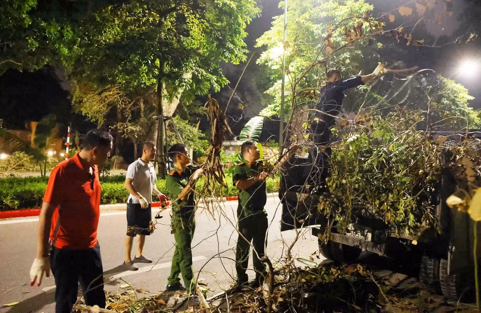 Cán bộ, chiến sỹ Công an phường Điện Biên, Quận Ba Đình xuyên đêm dọn dẹp cây gãy đổ sau cơn bão số 3 trên đường Hoàng Diệu. (Ảnh: Phạm Kiên/TTXVN)