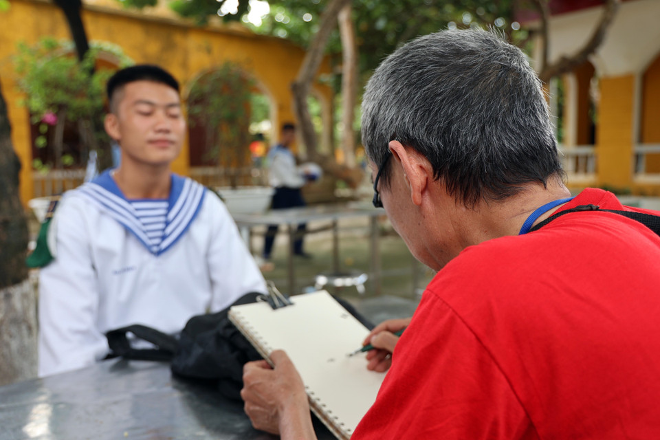 Họa sỹ Trần Nguyên Hiếu ký họa chân dung các chiến sỹ đảo Sinh Tồn. (Ảnh: Diệp Trương/TTXVN)