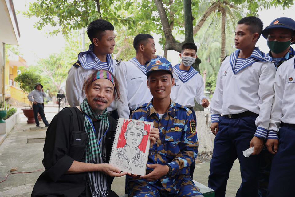 Anh Nguyễn Quang Trường (Etcetera Nguyễn), kiều bào Mỹ, tặng bức tranh ký họa chân dung cho các chiến sỹ Trường Sa. (Ảnh: Diệp Trương/TTXVN)