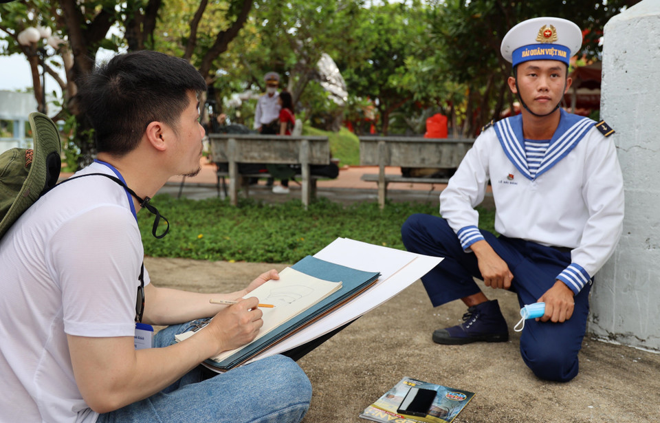 Họa sỹ Nguyễn Văn Trinh ký họa chân dung các chiến sỹ đảo Trường Sa. (Ảnh: Diệp Trương/TTXVN)