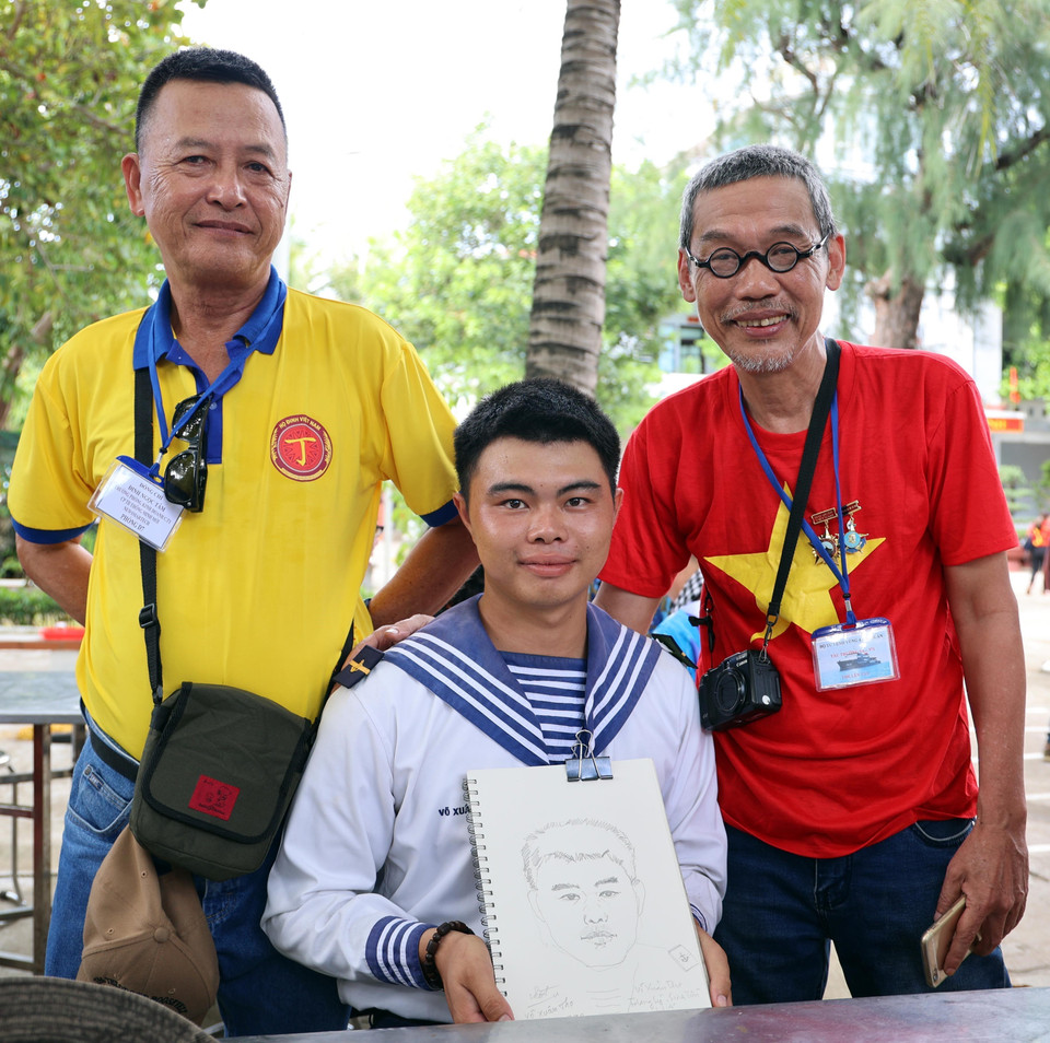 Họa sỹ Trần Nguyên Hiếu tặng tranh ký họa chân dung cho các chiến sỹ đảo Sinh Tồn. (Ảnh: Diệp Trương/TTXVN)