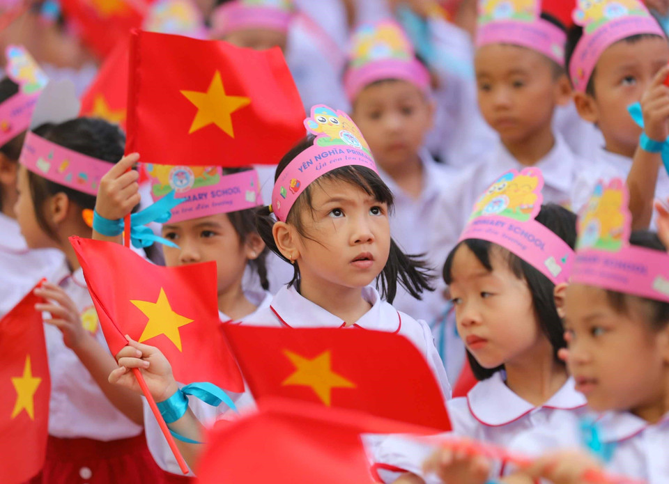 Cờ Tổ quốc trên tay, bé hân hoan vào lớp 1. (Ảnh: Thanh Tùng/TTXVN)