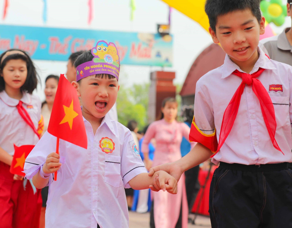Cờ Tổ quốc trên tay, bé hân hoan vào lớp 1. (Ảnh: Thanh Tùng/TTXVN)