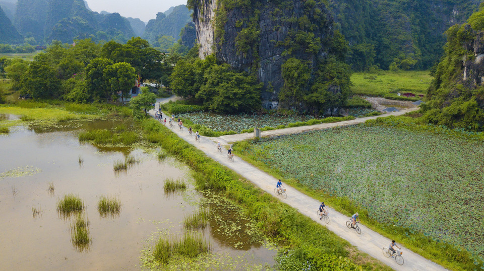 Du khách tự đạp xe khám phá cảnh vật Tam Cốc đầy thơ mộng, cảm tưởng như lạc vào chốn tiên cảnh khi xung quanh là núi cao, sông nước bao phủ. (Ảnh: Minh Đức/TTXVN)