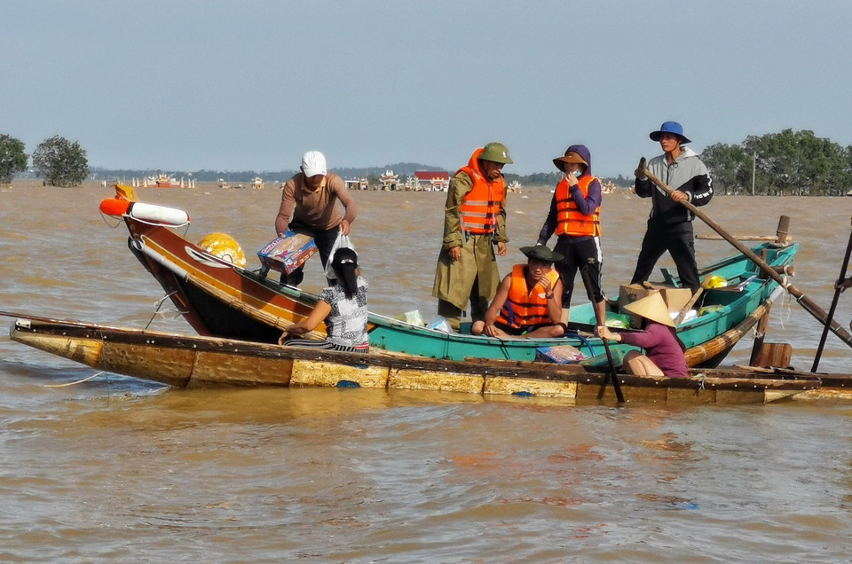 Người dân chèo thuyền đi lấy hàng cứu trợ do địa hình phức tạp khiến lực lượng chức năng không thể tiếp cận. (Ảnh: Thành Đạt/TTXVN)
