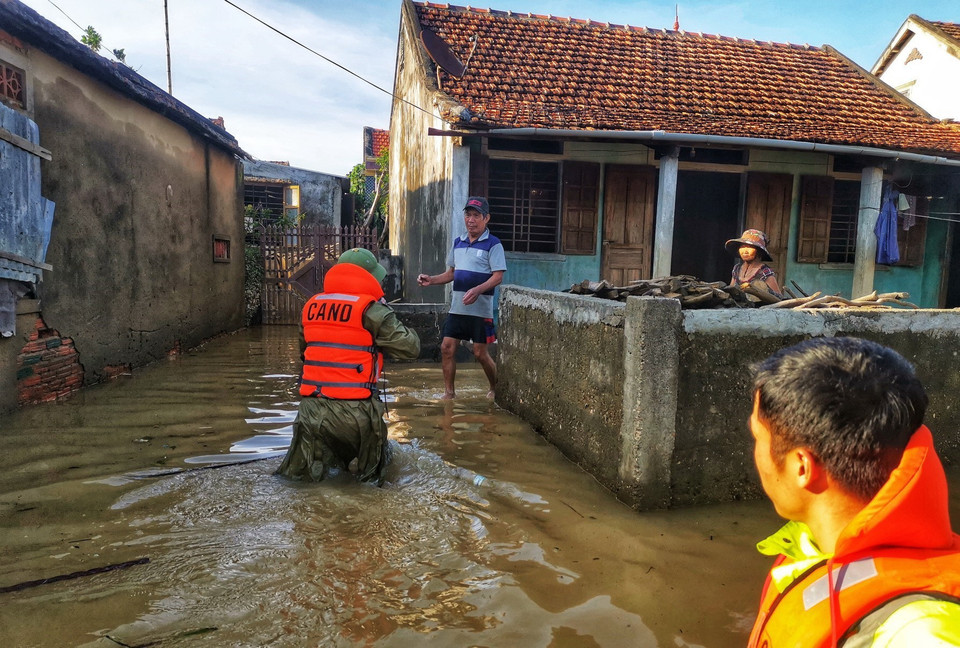 Lực lượng công an huyện Lệ Thủy lội nước, đưa hàng cứu trợ đến những gia đình bị cô lập trong nước lũ. (Ảnh: Thành Đạt/TTXVN)