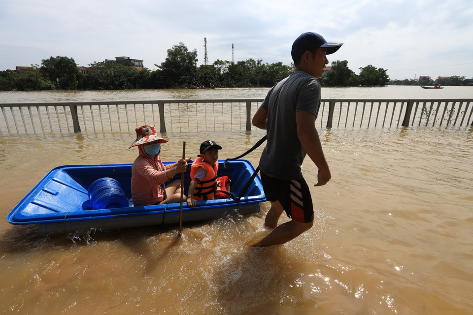 Người dân Lệ Thủy sử dụng đủ mọi cách để di chuyển trong nước lũ. (Ảnh: Thành Đạt/TTXVN)