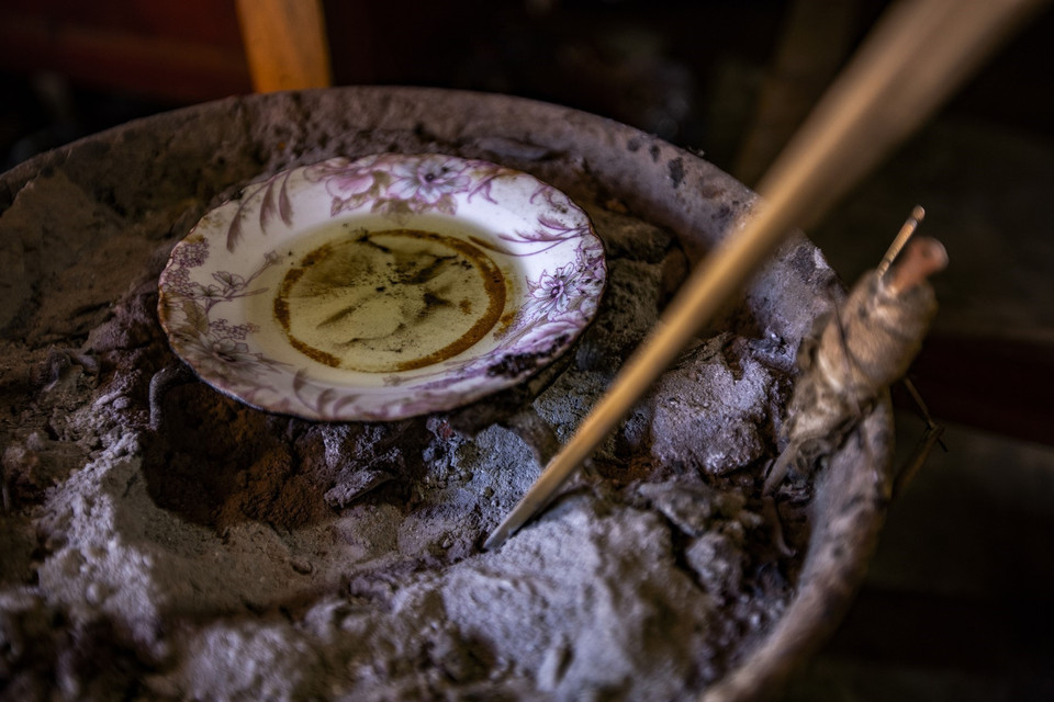 Sáp ong cho vào đĩa nhỏ để lên trên than hoa đang cháy để duy trì độ nóng, giúp sáp in được mịn và sắc nét. (Ảnh: Trọng Đạt/TTXVN)