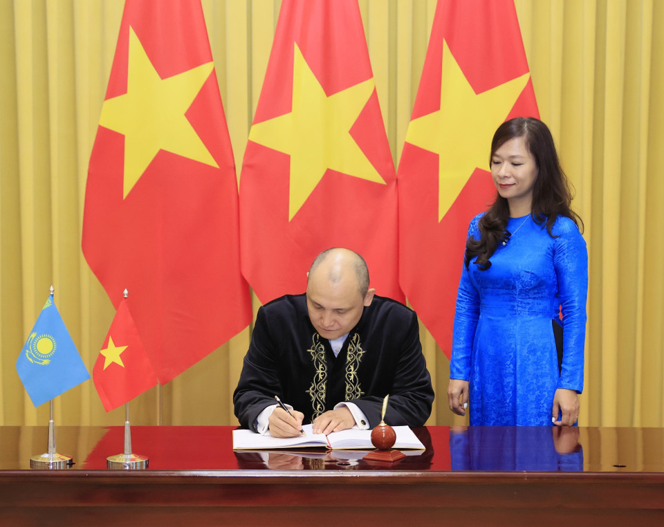 Đại sứ Kazakhstan Kanat Tumysh viết lưu bút. (Ảnh: Thống Nhất/TTXVN)