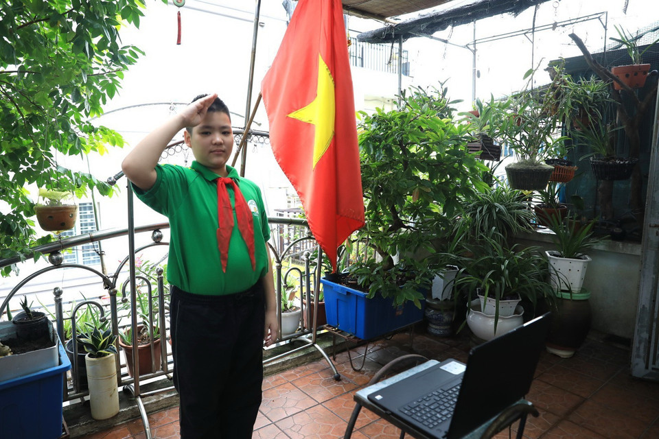 Học sinh Trần Chính Nguyên, lớp 6A1 trường THCS Nguyễn Tri Phương thực hiện nghi lễ chào cờ tại lễ khai giảng năm học mới bằng hình thức trực tuyến. (Ảnh: Thành Đạt/TXVN)
