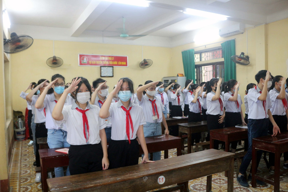Các học sinh trường THCS Trần Phú (Phủ Lý) thực hiện nghi lễ chào cờ trong buổi khai giảng ngay tại lớp thông qua hệ thống trực tuyến của trường. (Ảnh: Đại Nghĩa/TTXVN)