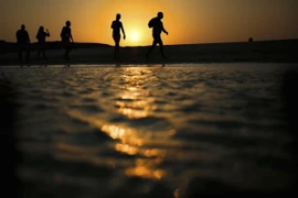 Du khách đi dạo trên bãi biển Đảo Giftun khi Mặt Trời lặn trên Biển Đỏ ở Hurghada (Ai Cập). (Nguồn: AP)