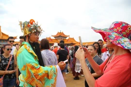 Du khách thích thú chụp ảnh lưu niệm cùng nhân vật Thần Tài trong dân gian của người châu Á. (Ảnh: Hồng Minh/TTXVN)