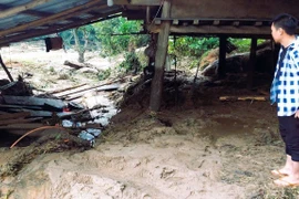 Người dân ngậm ngùi khi chứng kiến hậu quả của lũ quét tàn phá nhà cửa. (Ảnh: TTXVN phát)