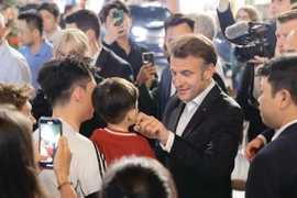 Tổng thống Pháp và Phu nhân gặp gỡ người dân trên đường tản bộ khu vực phố cổ Hà Nội, tối 26/5/2025. (Ảnh: TTXVN)