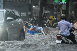 Một người dân bị ngã trên đường Quốc Hương khi di chuyển qua đoạn đường ngập. (Ảnh: TTXVN phát)