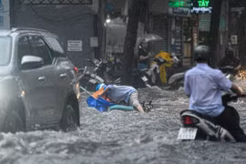 Một người dân bị ngã trên đường Quốc Hương khi di chuyển qua đoạn đường ngập. (Ảnh: TTXVN phát)