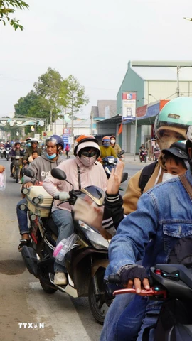 Những chai nước uống, những cái vẫy tay chào, những nụ cười… từ các tình nguyện viên của “Trạm dừng chân nghĩa tình” khiến nhiều người đi đường cảm thấy ấm lòng trên đường về quê. (Ảnh: Nhựt An/TTXVN)