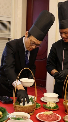 Quan chức ngoại giao tại Trung Quốc trải nghiệm cách chế biến một tô phở. (Ảnh: Hải Yến/TTXVN)