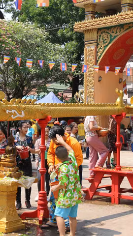 Trẻ nhỏ lấy nước tắm Phật xoa lên đầu người lớn để cầu chúc gặp nhiều may mắn trong dịp Tết cổ truyền Bun Pi May của Lào. (Ảnh: Xuân Tú/TTXVN)